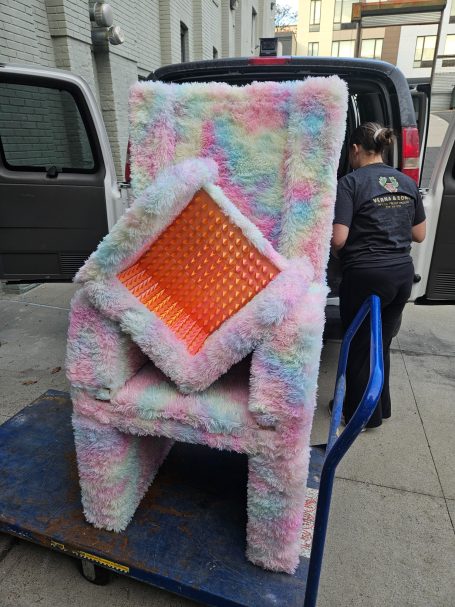 Colorful, fluffy chairs stacked on a cart outside a building.