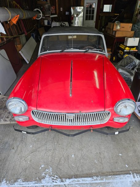 Classic red convertible car parked inside a garage.