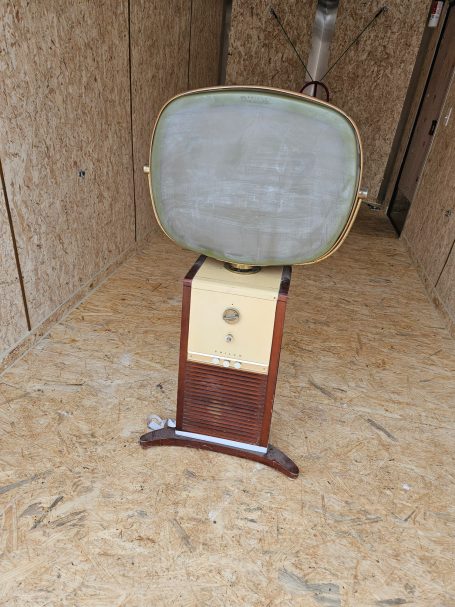 Vintage television set with a wooden base and a large, curved screen.